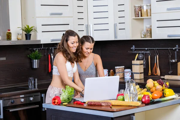 Two twin sisters looking for salad recipe on the Internet — Stock Photo, Image