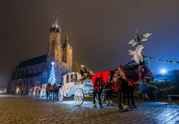 Rijtuigen voor toeristen rijden op de achtergrond van Mariacki kathedraal — Stockfoto