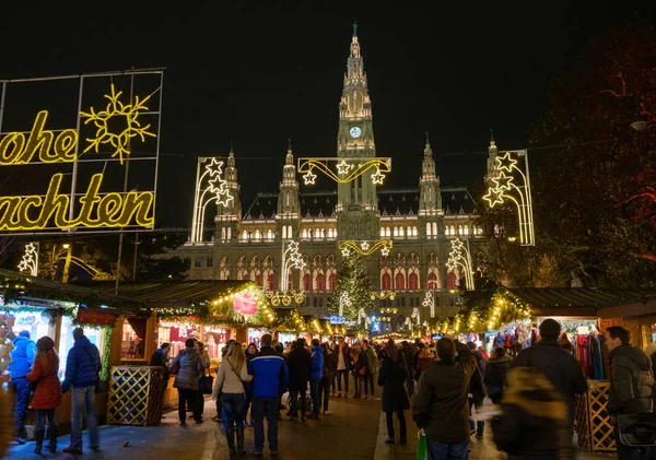 Mensen bezoek kerstmarkt in de buurt van stadhuis op avond — Stockfoto