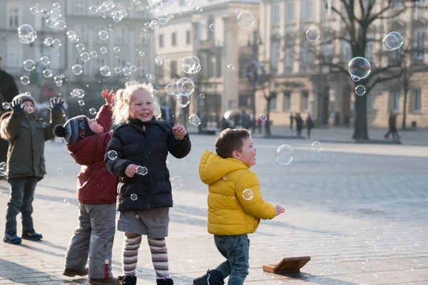 Niños de 4 a 5 años jugando con burbujas de jabón en la plaza —  Fotos de Stock