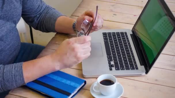 Чоловік працює за ноутбуком на дерев'яному столі . — стокове відео