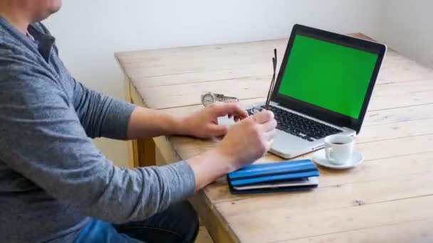 Mann arbeitet an einem Laptop auf einem Holztisch. — Stockvideo