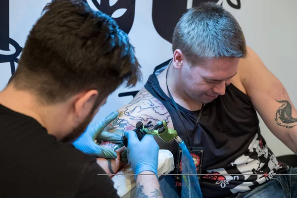 Художник делает татуировку для посетителя фестиваля татуировок — стоковое фото
