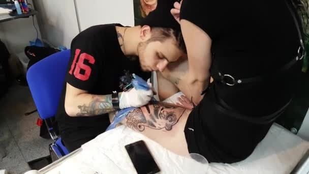 Художник делает татуировку для посетителя фестиваля татуировок — стоковое видео