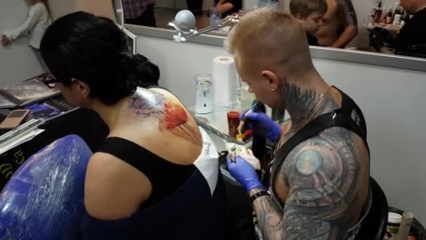 Художник делает татуировку для посетителя фестиваля татуировок — стоковое видео