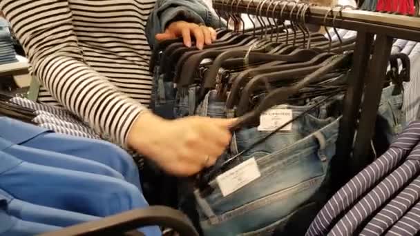 Mujer joven elige ropa — Vídeos de Stock