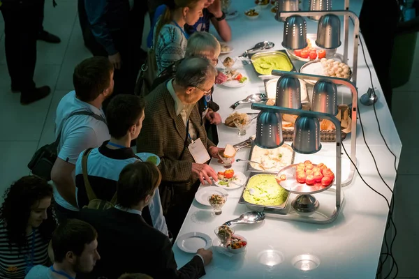 Folk tar boller med rosiner i kaffepause på en konferanse. – stockfoto