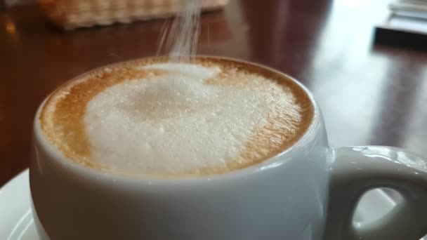 Socker som hälls i en kopp cappuccino — Stockvideo