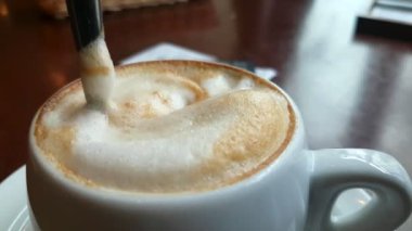 Kaşık şeker bir fincan cappuccino ile hareket ediyor