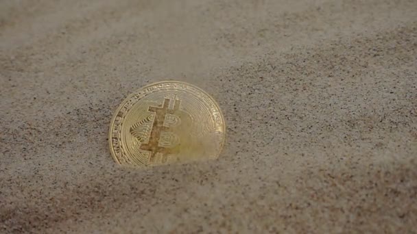 Gouden bitcoin munt is bedekt met zand — Stockvideo