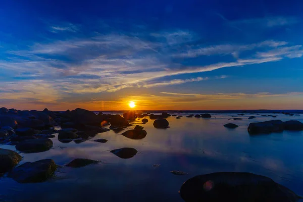 手前に石、海に沈む夕日 — ストック写真