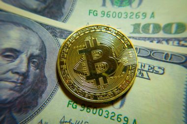 Altın bitcoin sikke 100 dolarlık banknot üzerinde.