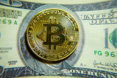 Altın bitcoin sikke 100 dolarlık banknot üzerinde.
