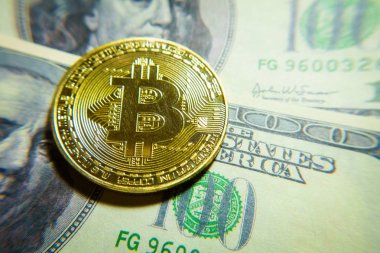 Altın bitcoin sikke 100 dolarlık banknot üzerinde.