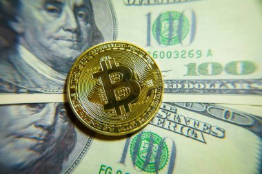 Altın bitcoin sikke 100 dolarlık banknot üzerinde.