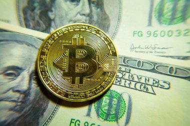 Altın bitcoin sikke 100 dolarlık banknot üzerinde.