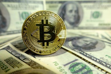 Altın bitcoin sikke 100 dolarlık banknot üzerinde.