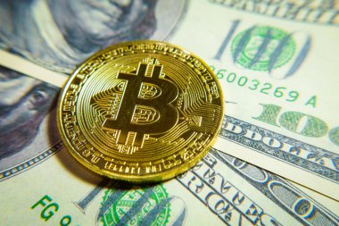 Altın bitcoin sikke 100 dolarlık banknot üzerinde.