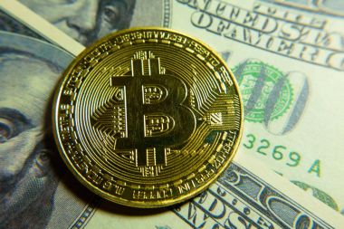 Altın bitcoin sikke 100 dolarlık banknot üzerinde.