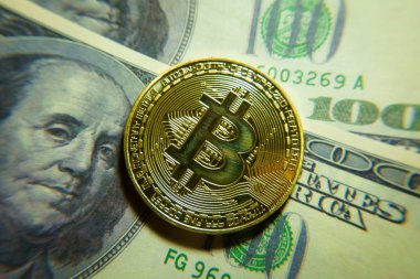 Altın bitcoin sikke 100 dolarlık banknot üzerinde.