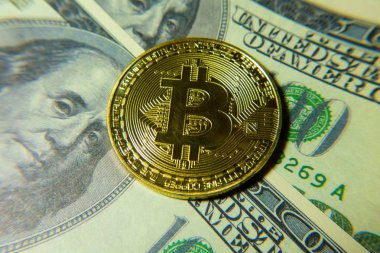 Altın bitcoin sikke 100 dolarlık banknot üzerinde.