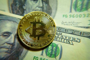 Altın bitcoin sikke 100 dolarlık banknot üzerinde.