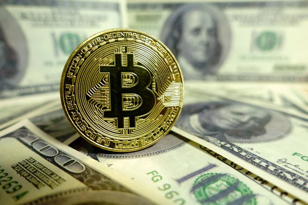 Altın bitcoin sikke 100 dolarlık banknot üzerinde.