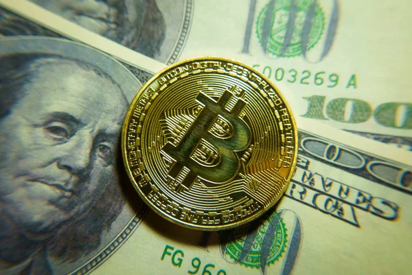 Altın bitcoin sikke 100 dolarlık banknot üzerinde.