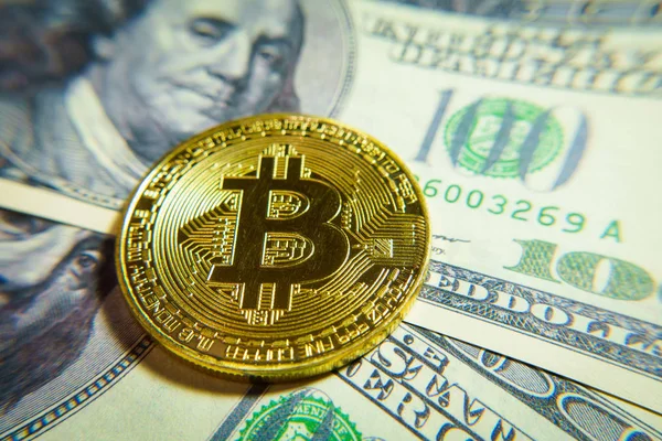 Altın bitcoin sikke 100 dolarlık banknot üzerinde.