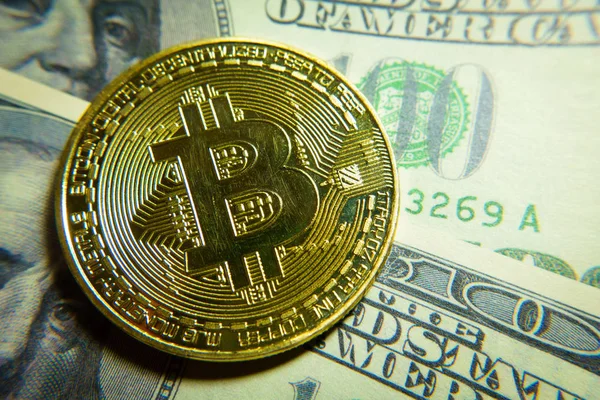 Altın bitcoin sikke 100 dolarlık banknot üzerinde.