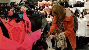 Genç kadın alışveriş merkezinde giysiler seçmek