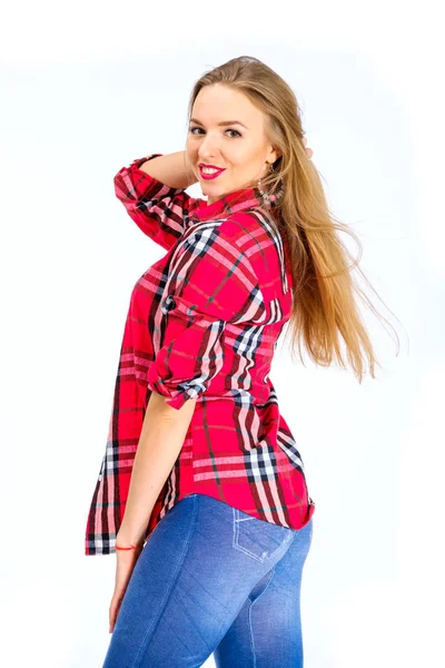 Young sexy woman dressed in jeans and checkered shirt posing in studio — Stock Photo, Image