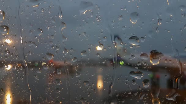Аэропорт через окно самолета, идет дождь — стоковое видео