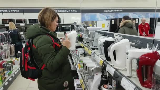 Mujer joven elige una batidora en un supermercado de electrodomésticos — Vídeos de Stock