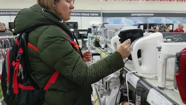 Молодая женщина выбирает миксер в супермаркете бытовой техники — стоковое видео