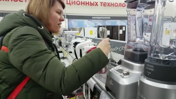 Молодая женщина выбирает миксер в супермаркете бытовой техники — стоковое видео