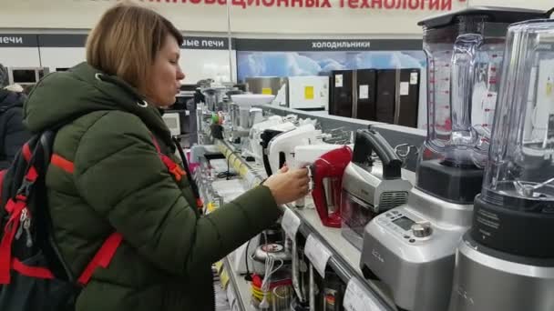 Mujer joven elige una batidora en un supermercado de electrodomésticos — Vídeos de Stock