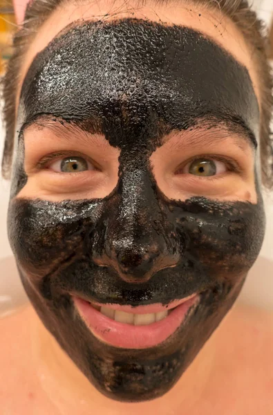 Woman uses a black facial mask — Stock Photo, Image