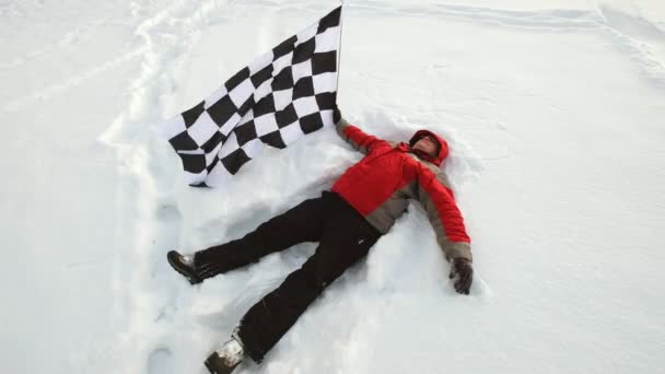 Ο άνθρωπος κείτεται στο χιόνι με τη σημαία του τερματισμού — Αρχείο Βίντεο