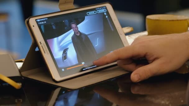 Man verkennen Tesla bedrijf site met behulp van tablet pc in café. — Stockvideo