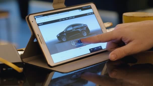 Man verkennen Tesla bedrijf site met behulp van tablet pc in café. — Stockvideo