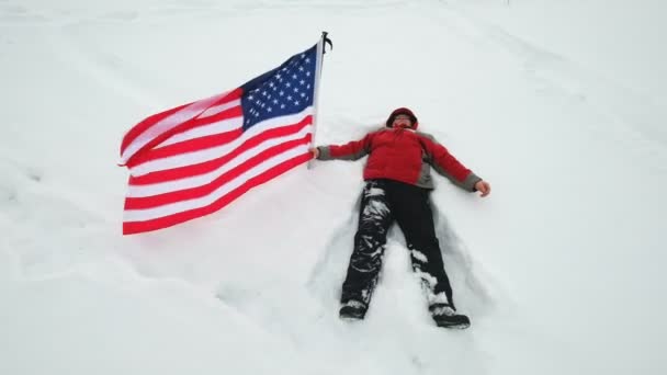 男人挥舞着我们的旗帜躺在雪地里 — 图库视频影像