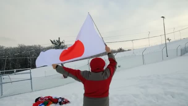 Hombre ondeando una bandera de Japón en invierno en la pista de esquí — Vídeos de Stock