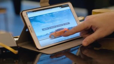 Adam seyir için ebay sitesi keşfetmek kafede tablet pc kullanarak Tesla ikinci el araç.