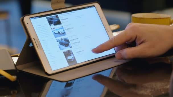 Muž zkoumání ebay webu hledáte ojetý vůz Tesla používající počítač tablet pc v kavárně. — Stock video