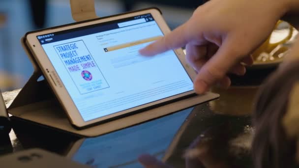 Онлайн-покупки на сайте Amazon с помощью tblet PC в кафе — стоковое видео