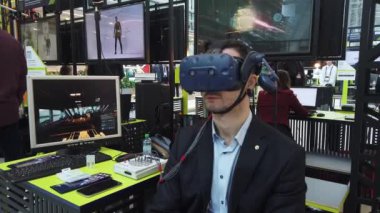 Sergi ziyaretçisi sanal gerçeklik miğferini bilgisayar oyunu için test ediyor
