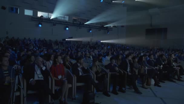 Besucher eines Wirtschaftsforums sehen eine Präsentation auf dem Bildschirm in der Halle — Stockvideo