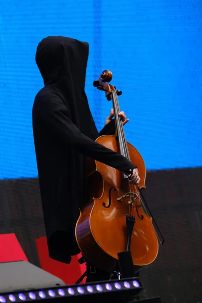 Hombre con una túnica negra con capucha toca el violonchelo — Foto de Stock