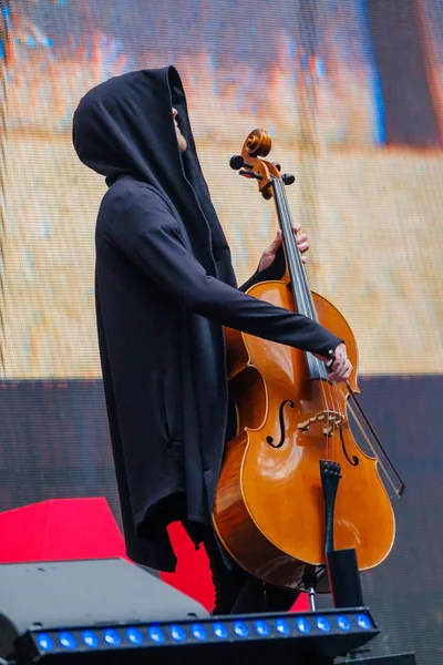 Man i svart rock med huva spelar cello — Stockfoto